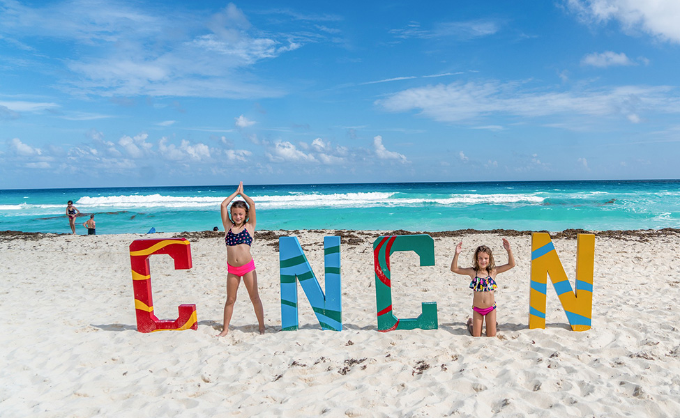 Kids at the Cancun beach sign 