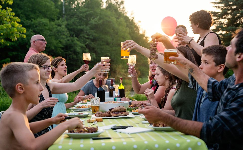 People of all ages gather around the table outside 