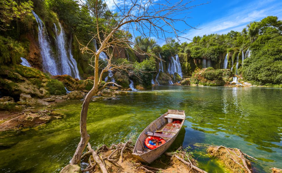 Small boat in the Kravice waterfall's pool 